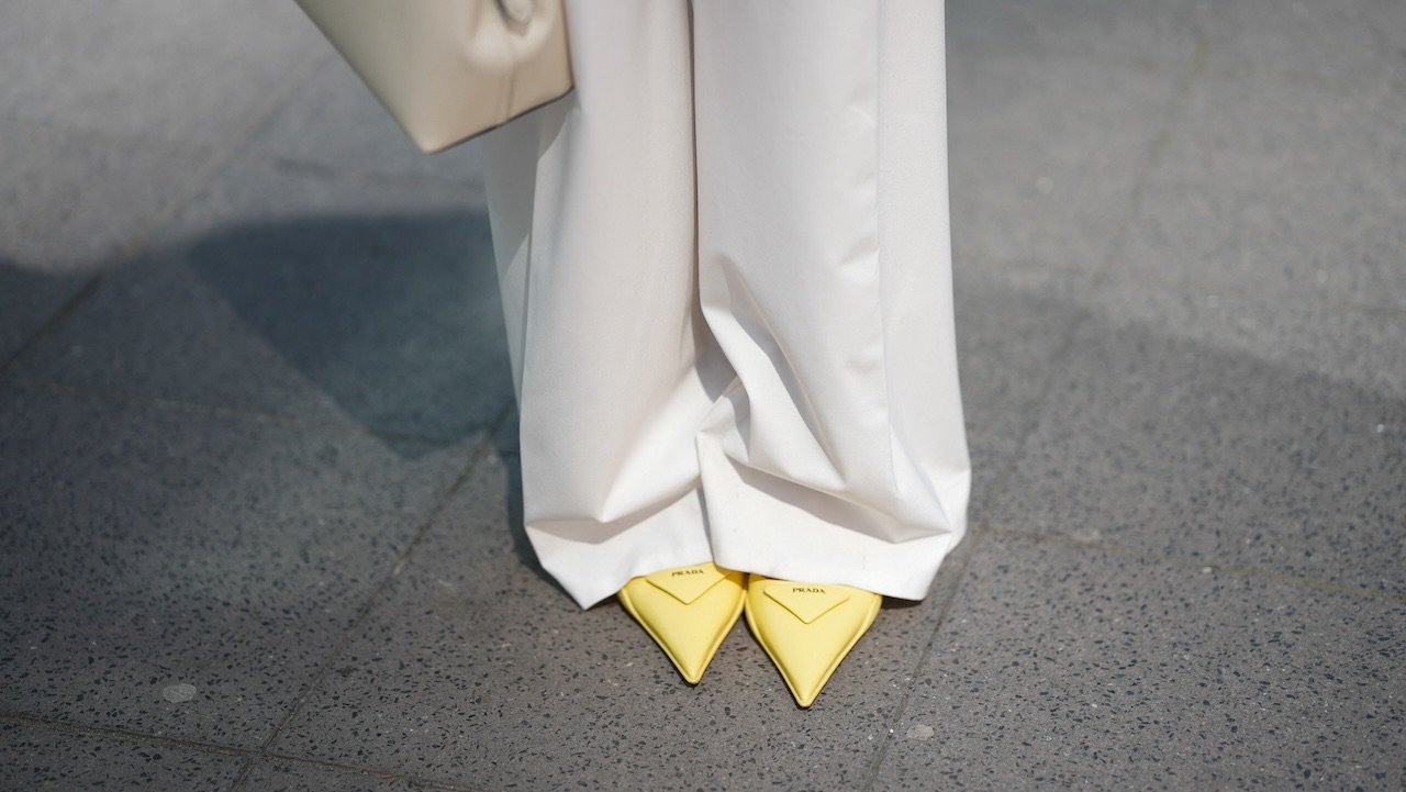 FRANKFURT AM MAIN, GERMANY - MAY 12: Angelika Hanel is seen wearing a Limited Edition white pleated wide legsuit pants from Massimo Dutti, a T-Lock leather handbag in milk white from Toteme, a pair of yellow slingback pointed kitten-heels with triangle shaped logo detail from Prada on May 12, 2025 in Frankfurt am Main, Germany. (Photo by Moritz Scholz/Getty Images)